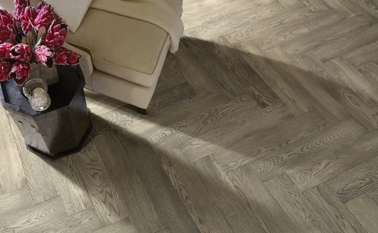 Herringbone pattern hardwood floor with beige chair. 